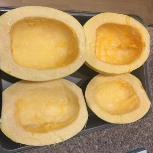 Spaghetti squash halves with salt to remove water content on baking sheet.